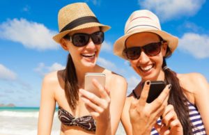 two-women-staring-at-cell-phones-on-a-beach
